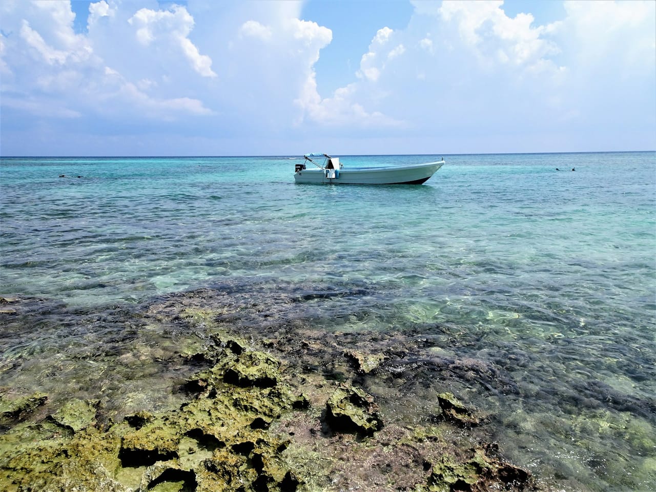 Bote anclado sobre un arrecife somero visible bajo el agua clara