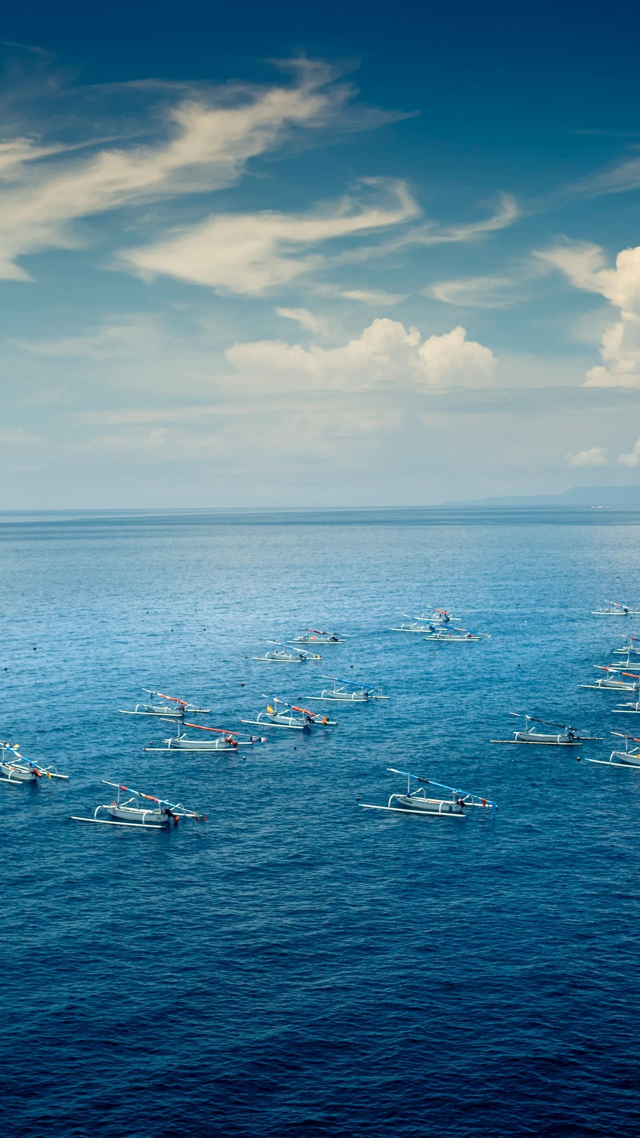 Mar abierto azul profundo con botes de pesca a lo lejos